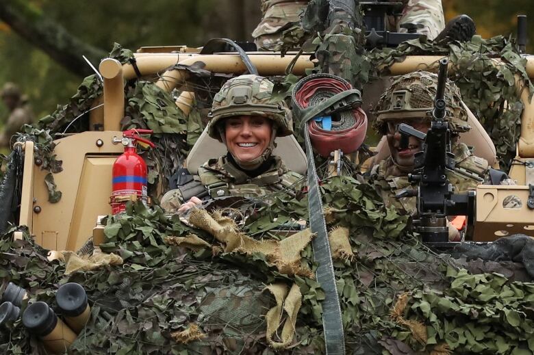 A person wearing camouflage gear is seen in an armoured vehicle.