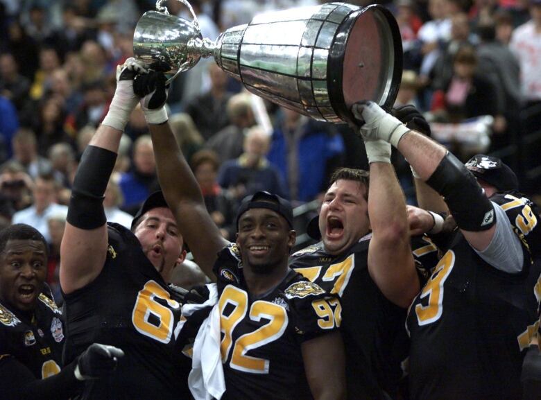 Member of the Hamilton Tiger-Cats hoist the Grey Cup after their victory over Calgary Stampeders  in Vancouver Sunday,  Nov. 28, 1999.