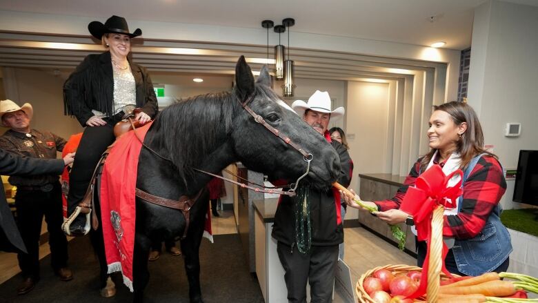 Diane Wensel, left, rides Tuffy the horse into the lobby of a hotel as the annual tradition kicks off Grey Cup festivities ahead of the 110th CFL Grey Cup between the Winnipeg Blue Bombers and Montreal Alouettes in Hamilton, Ont., on Thursday, November 16, 2023. 