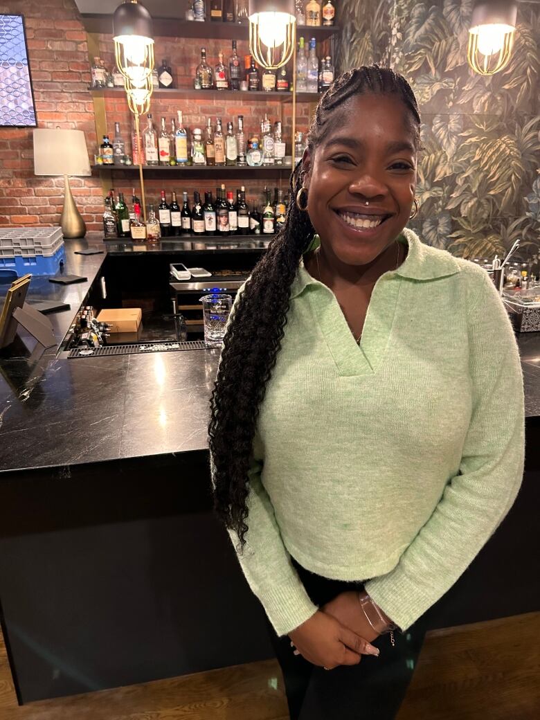 A woman standing in front of a bar and smiling at the camera