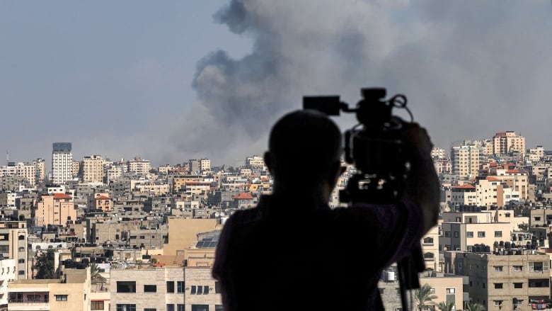 A camera operator captures images of the aftermath of Israeli airstrikes within Gaza City on Oct. 12, 2023.