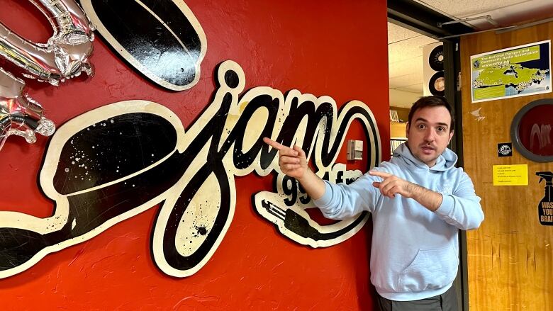 A man points to a sign in a radio station.