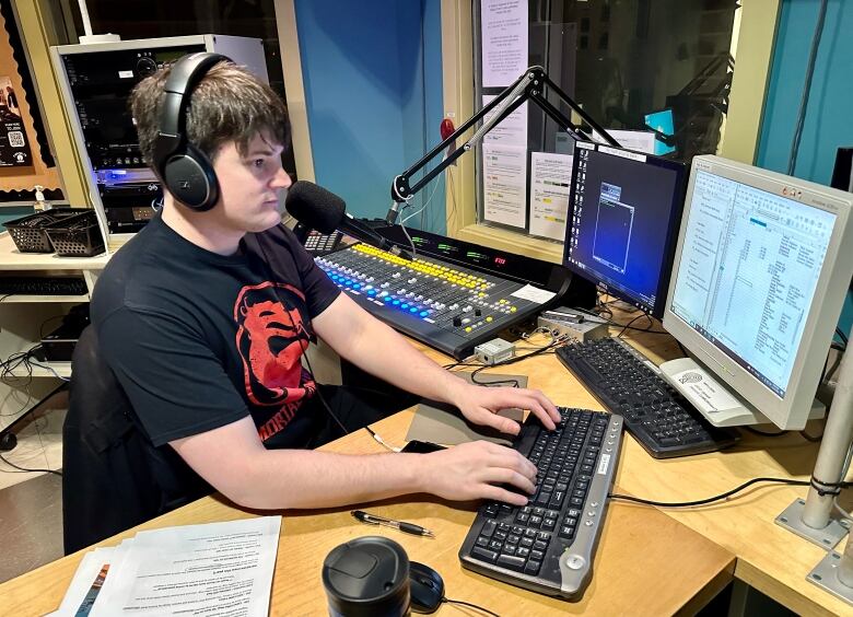 A man works in a broadcast booth at a radio station.