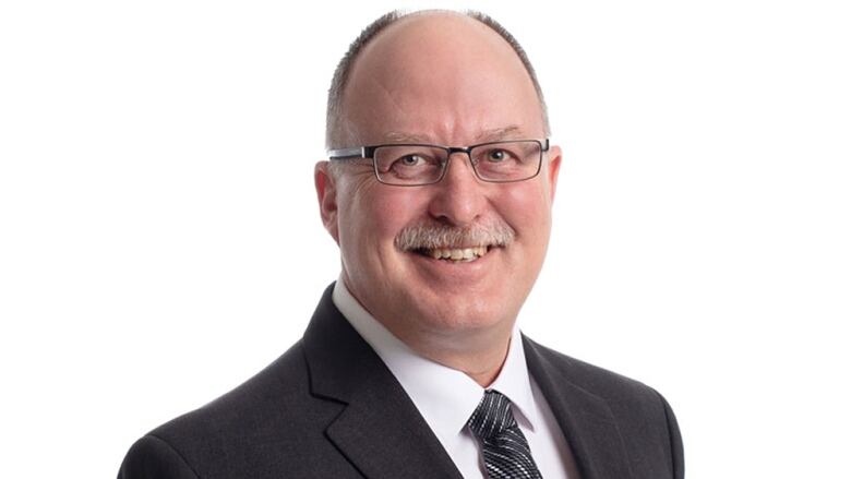 A balding man wearing glasses smiles for a portrait.