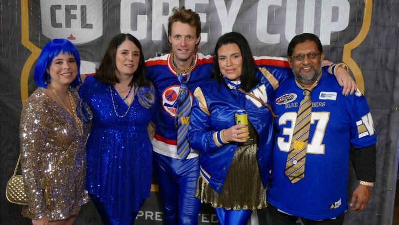 Five people standing dressed in different blue and gold outfits