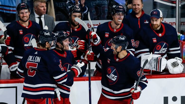 Hockey players gather in front of the sidelines.