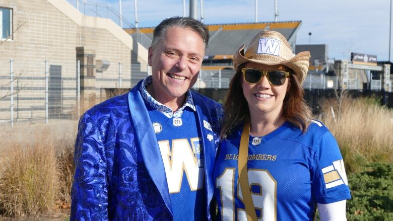 A man and a woman standing outside in blue shirts