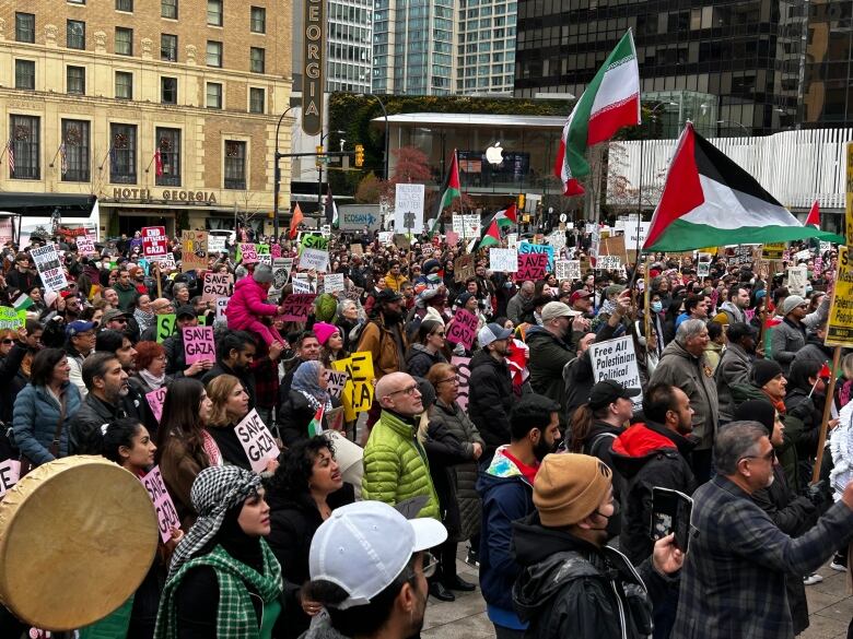 Hundreds of people wave Palestinian flags and placards asking for a ceasefire.