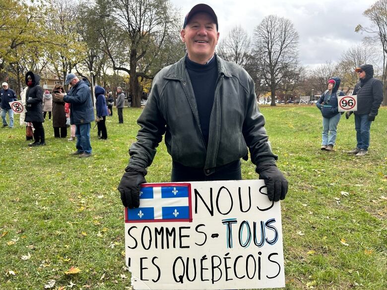 A man holds a sign reading, 