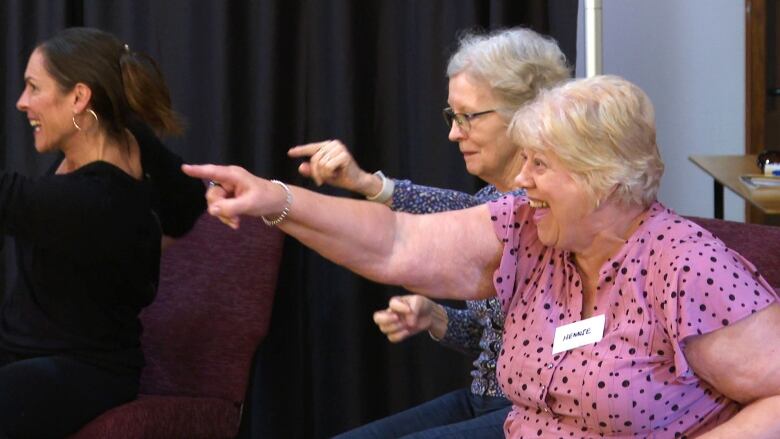 People dancing while sitting on chairs.