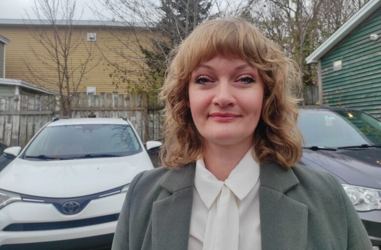 blonde woman standing outside with cars in the background