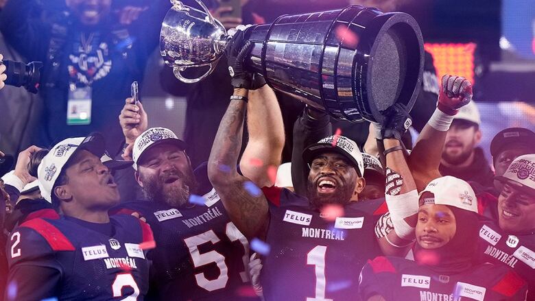 Montreal Alouettes player hoists Grey Cup over his head while surrounded by his teammates after their victory over the Winnipeg Blue Bombers in the 110th CFL championship.