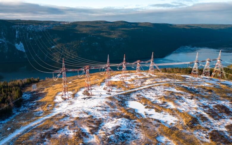 Power lines span across a river in winter.