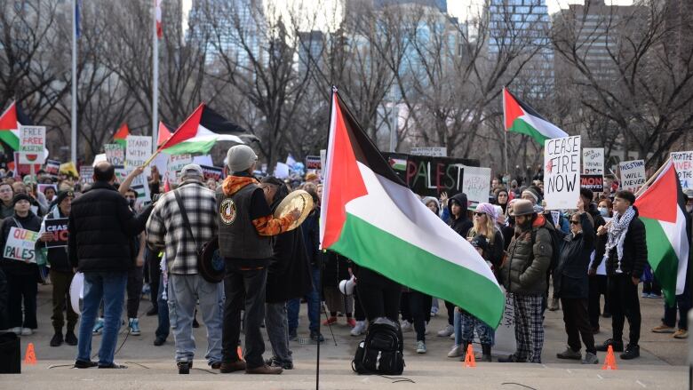 a palestinian flag is seen with several protesters behind on a city street 