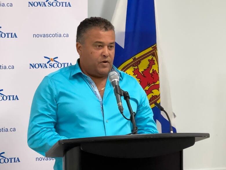 A man in a blue shirt stands at a podium. 