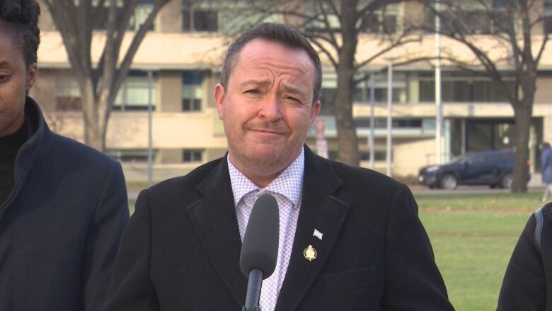 A man stands outside behind a microphone.