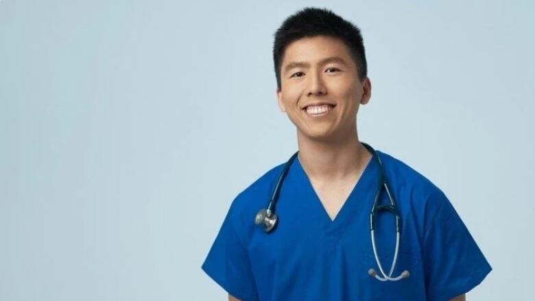 A man in medical scrubs poses for a photo.