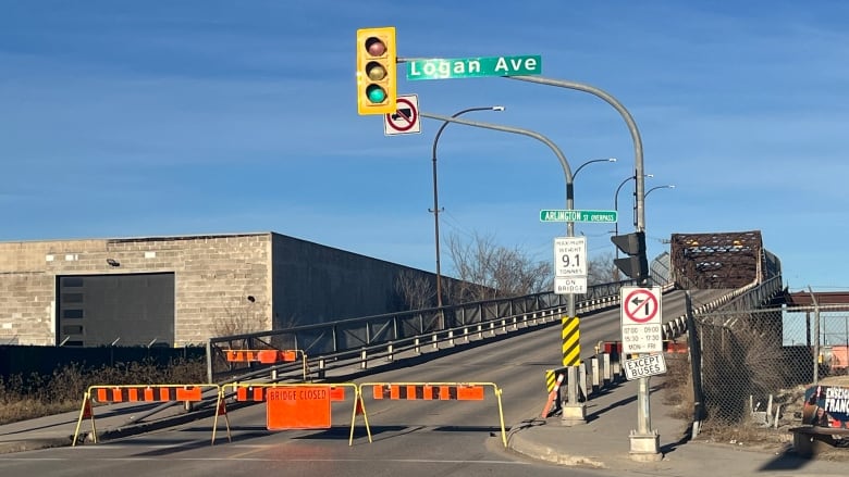 A bridge is pictured. It's opening is blocked off by orange and black metal signs.