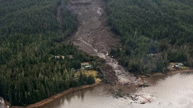 An aerial view of a landslide on the side of a mountain, into the water.