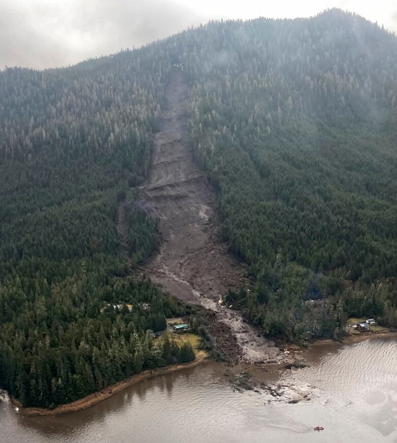 An aerial view of a landslide on the side of a mountain, into the water.