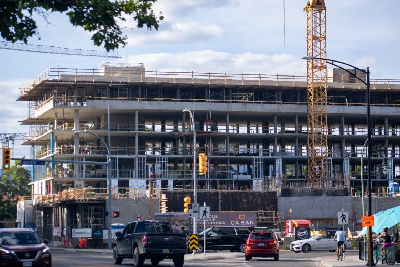 A condo building is pictured under construction next to a busy neighbourhood intersection.