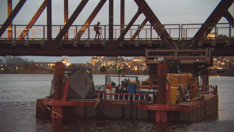 A person walks over a bridge at night.