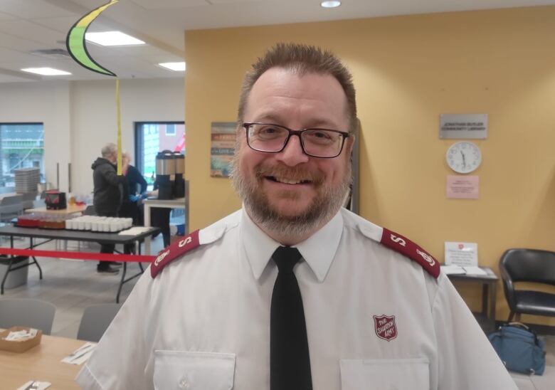 Man wearing white uniform and glasses, smiling.