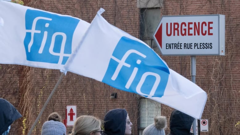 Nurses picket in front of a building. 