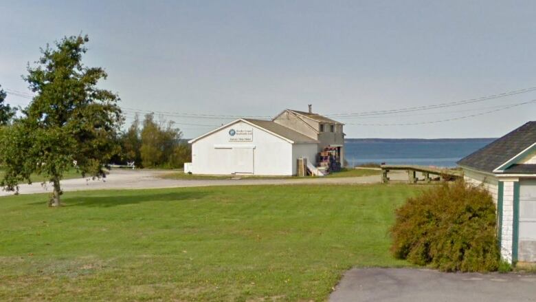 A small white industrial building on the coast 