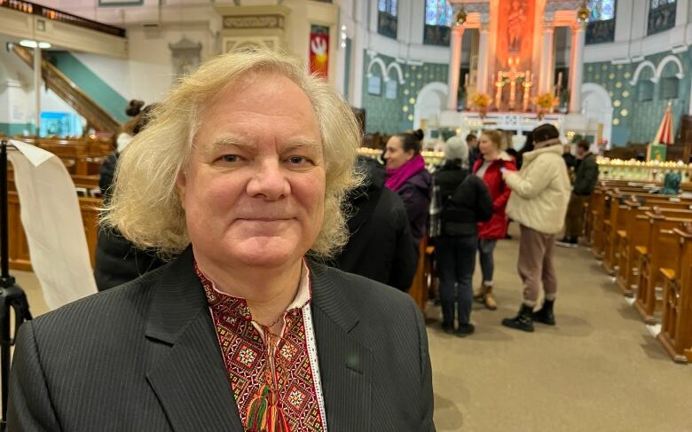 A man is pictured in a church with a large crowd of people behind him.