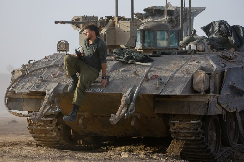 An Israeli soldier disembarks from an armoured personnel carrier near the Israel-Gaza border on its Israeli side during a temporary truce between Hamas and Israel, in southern Israel, November 26, 2023. 