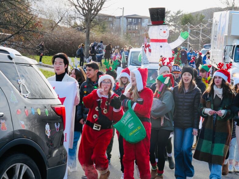 dozens of people stand in front of a giant inflatable snowman.