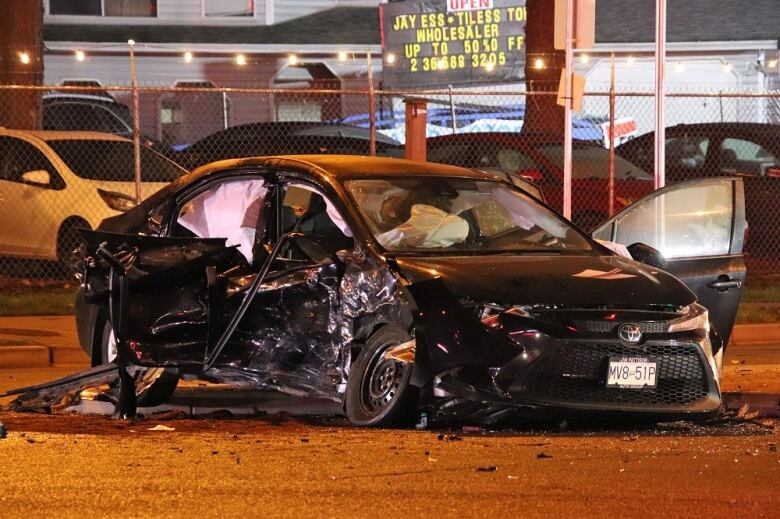 A black car is severely damadged on the left side, the airbags can be seen deployed. 