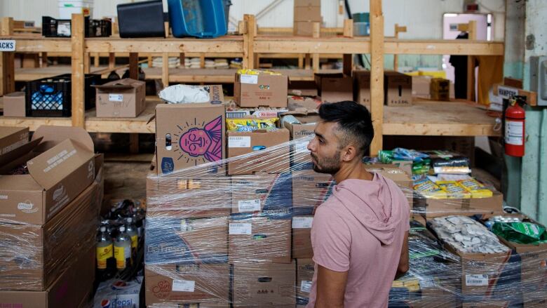 Man stands in front of a pile of boxes.