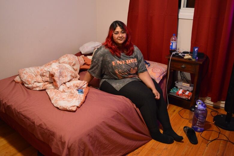 A woman sits on her bed