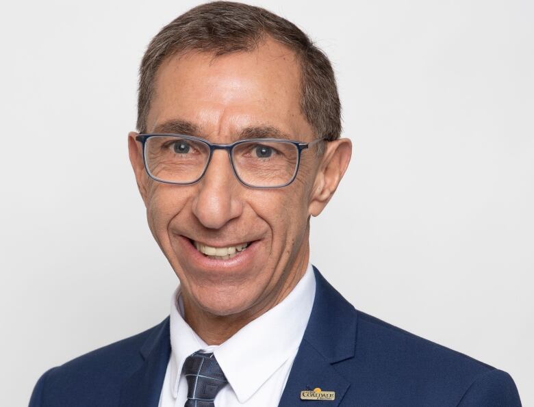 A man with a tie and suit smiles at the camera.