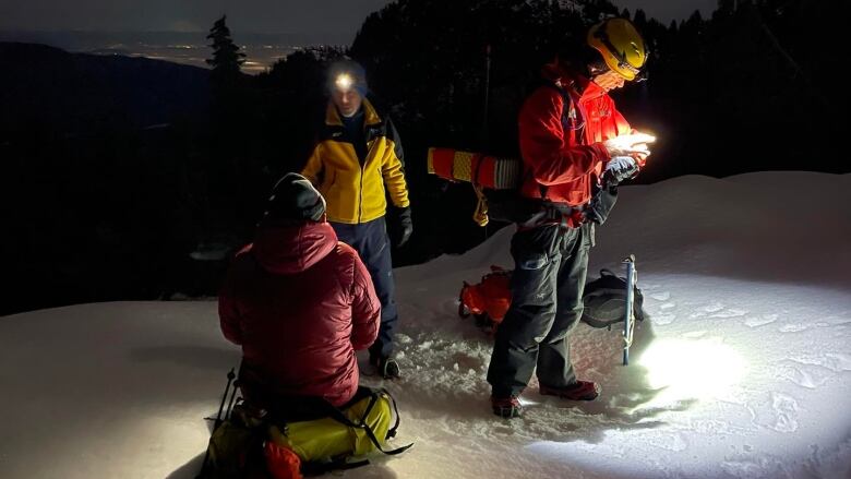 A group of rescuers wearing thermal gear on a snowy mountain.