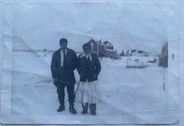 An old photo of a couple standing in the snow outside a wooden cabin in northern Quebec.