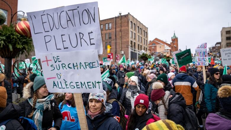 A large group of demonstrators, with one holding a French sign reading, 