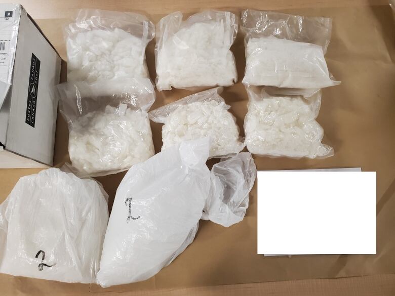 Eight bags of white powder and drugs is seen in a police photo.