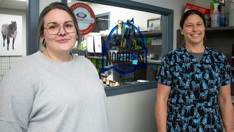 Two women stand by a sign that says North of 55 Veterinary Services.