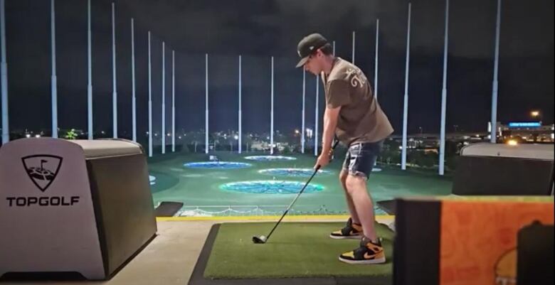 Man ready to take golf swing at the tee of a driving range.