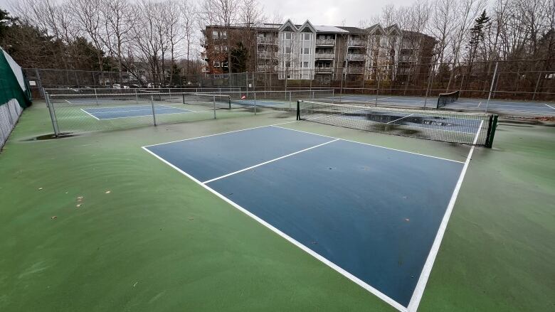 A fenced-in area with a green floor painted with white lines.