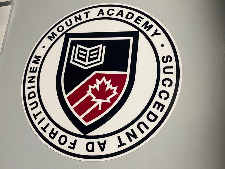 A school logo is displayed on the wall of the school. The logo has a book and a Canadian maple leaf. 