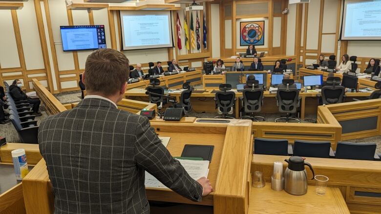 a man at a podium speaks with a room with seated people