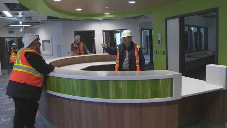 People wearing hi-viz jackets stand inside the foyer of a hospital.