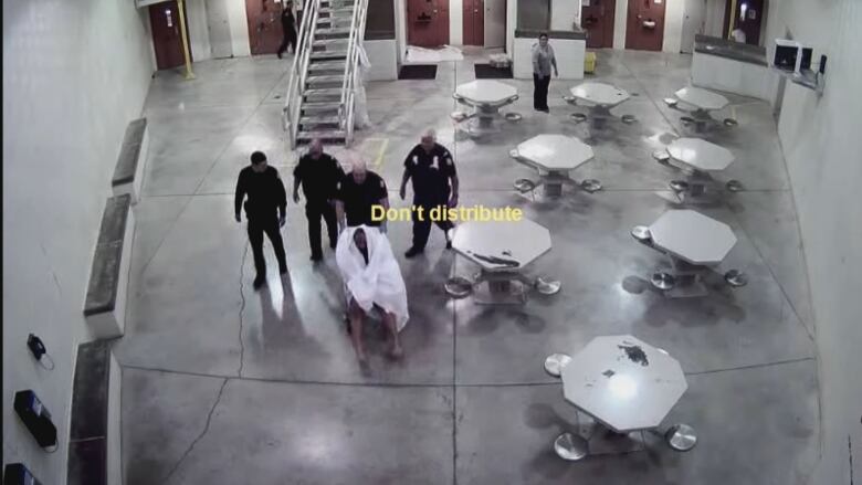 A still of an approximately minute-long video shows a group of health care staff and a jail manager moving Soleiman Faqiriin a wheelchair from one his cell in one part of the jail to a maximum segregation unit