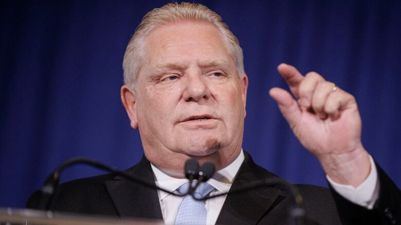 Premier Doug Ford gestures with his left thumb and index finger held close together.  