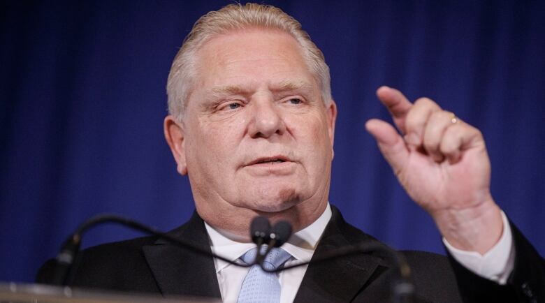 Premier Doug Ford gestures with his left thumb and index finger held close together.  