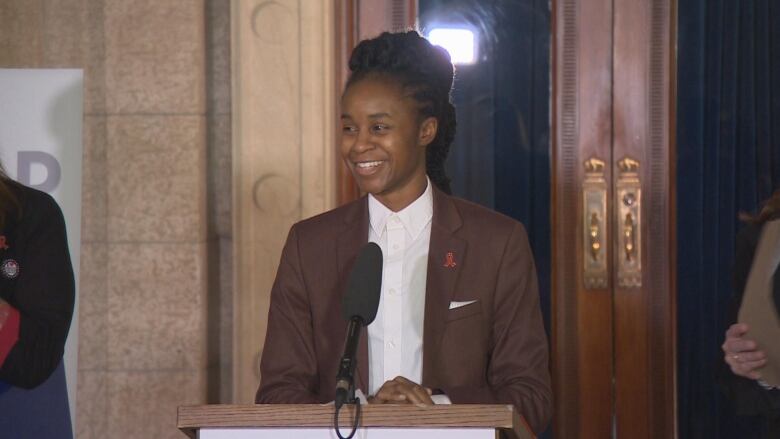 A politician in a maroon suite and white shirt speaks into a microphone.